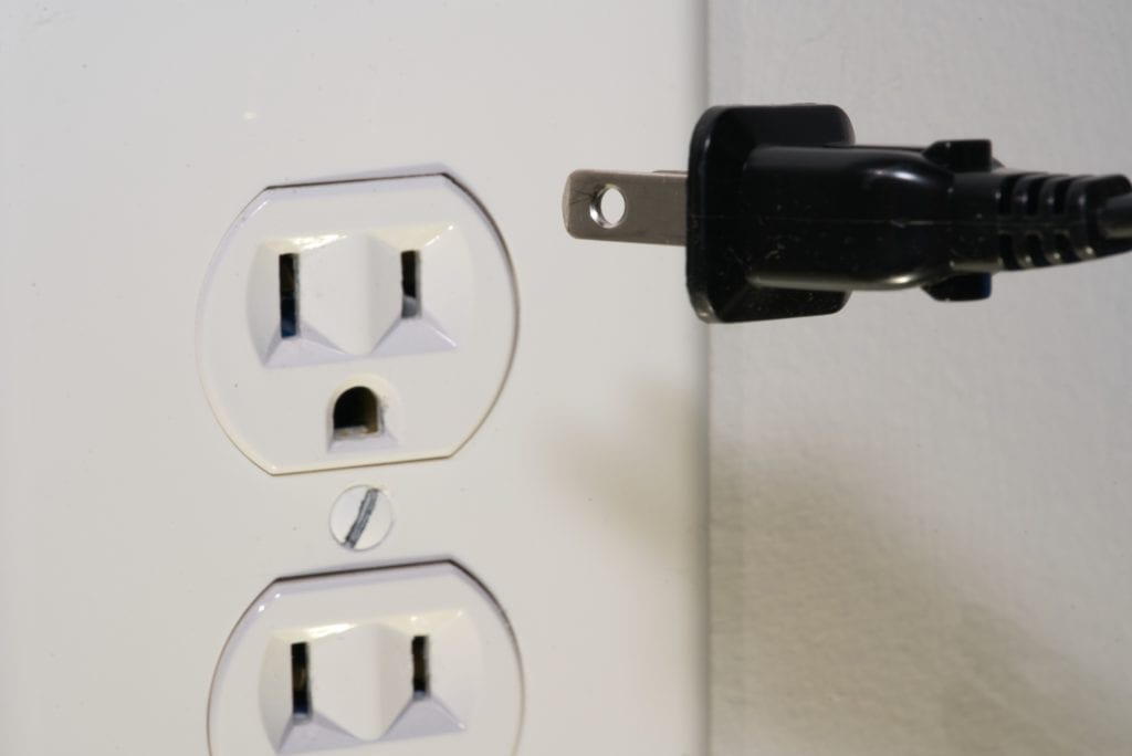 A black cord connected to a white outlet.
